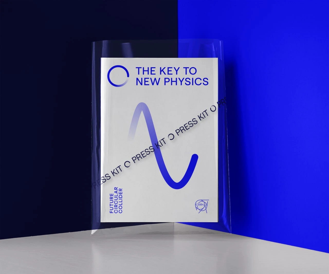 An FCC press kit with a blue wave-like line, The Key to New Physics headline and a transparent sleeve.