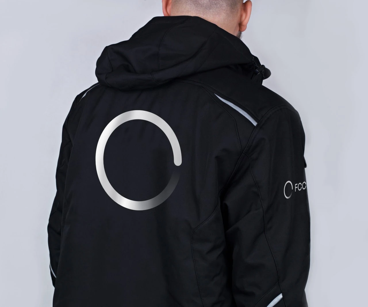 A person seen from behind wearing a black jacket with a large pale open circle.